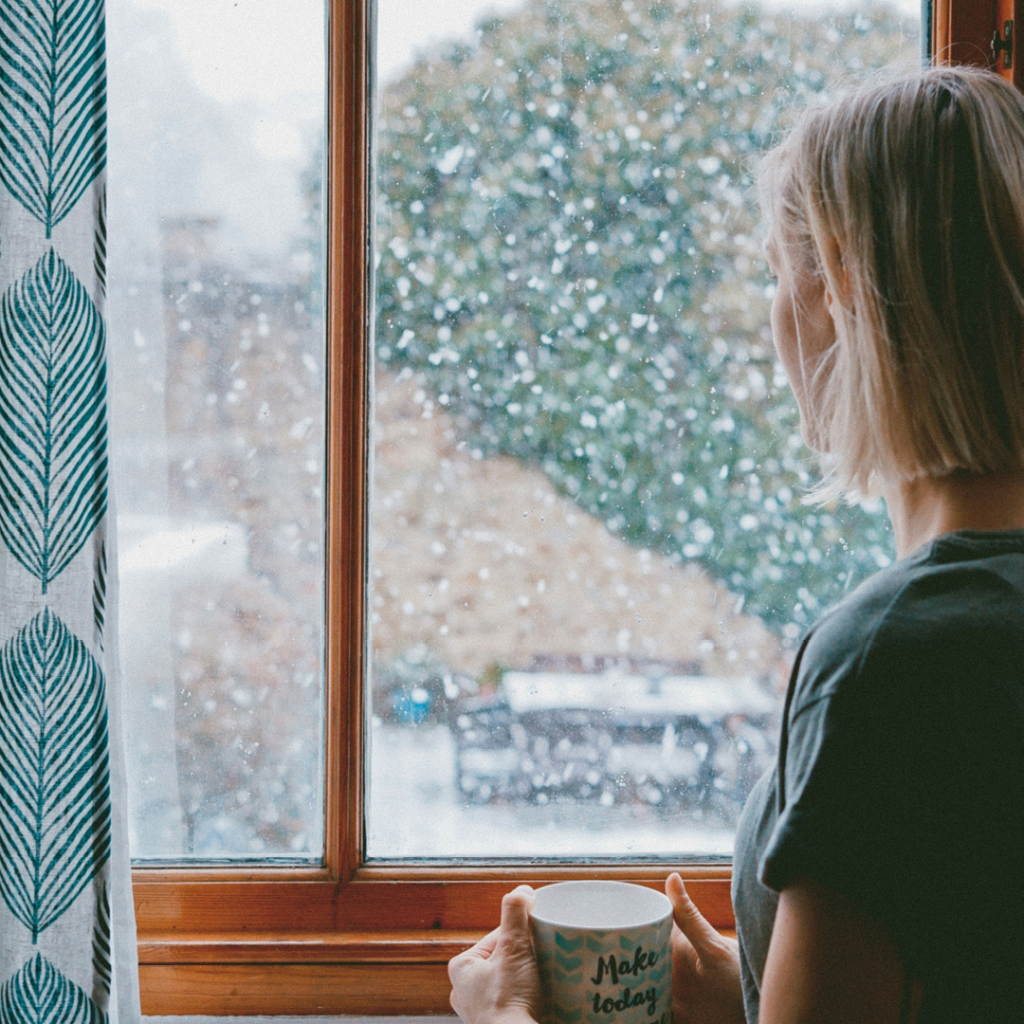 Woman looking out window at snow